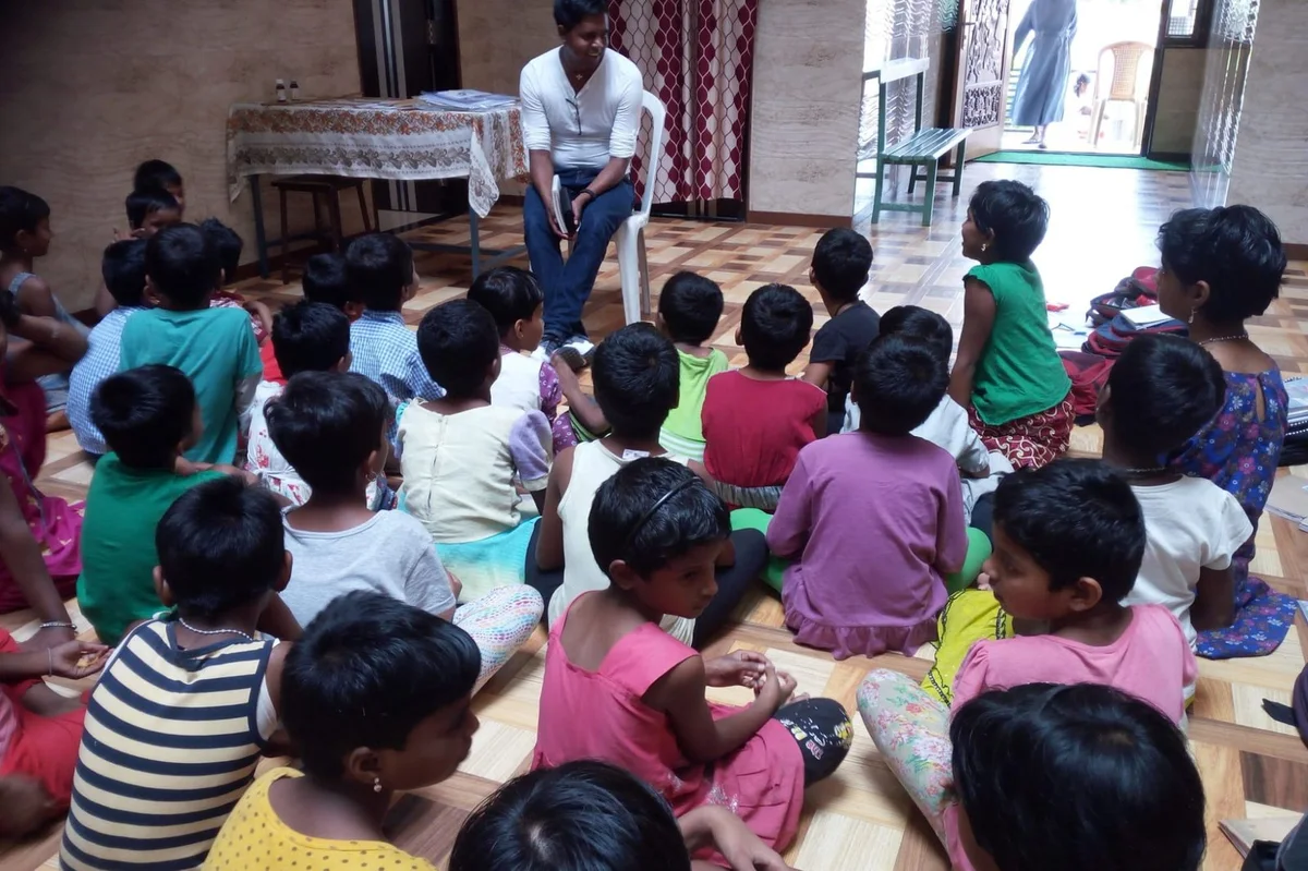 Nikhil Schmidt sitzt vor einer Gruppe von Kindern in Indien
