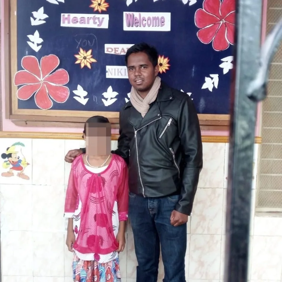 Nikhil Schmidt in einer Schule in Indien vor einer Willkommenstafel